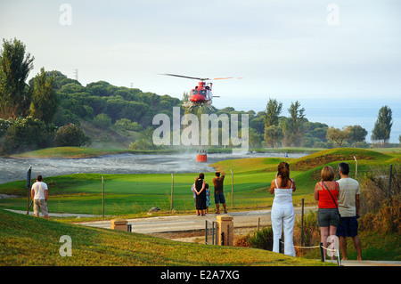 Bell 412 elicottero (registrazione N167EH) raccolta di acqua per la lotta contro gli incendi da un campo da golf lago, Cabopino Golf, Spagna. Foto Stock