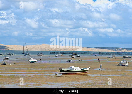 Francia, Gironde, Baia di Arcachon, Cap Ferret, gli uomini camminare sulla sabbia a bassa marea con barche nel mezzo delle Dune du Pyla in Foto Stock