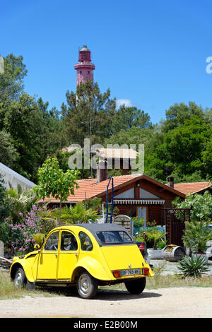 Francia, Gironde, Baia di Arcachon, Cap Ferret, giallo auto nella parte anteriore del legno di un piccola casa ai piedi di un faro Foto Stock