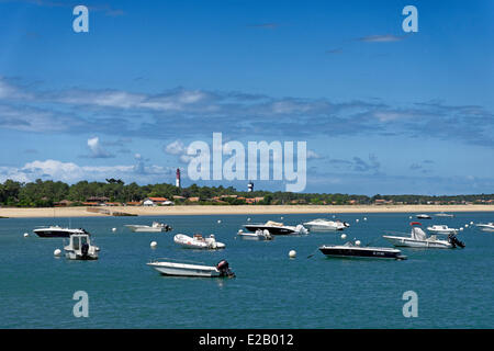 Francia, Gironde, Baia di Arcachon, Cap Ferret, Plage du Phare, barche a motore che sono ancorate al largo della spiaggia di fronte di un faro Foto Stock