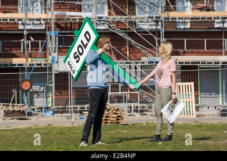 Coppia giovane con blueprint è felice di fronte alla loro nuova casa costruita appena acquistati Foto Stock