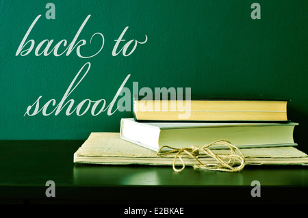 Alcuni libri su una scrivania e il testo si torna a scuola scritto su una lavagna verde Foto Stock