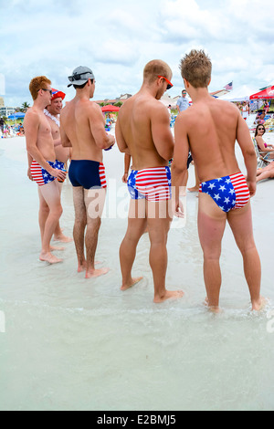 Un gruppo di collegio patriottico-di età compresa tra gli uomini a stelle e strisce abiti nuotare puntone la loro roba sulla spiaggia il 4 luglio Foto Stock