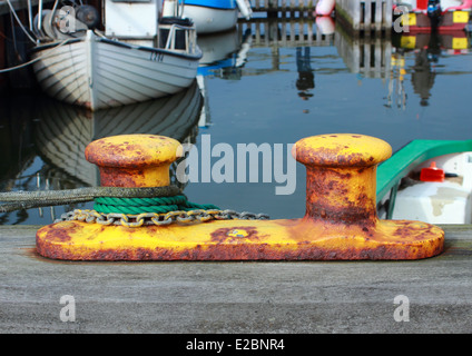 Bollard metallico al piccolo porto di pescatori con corde e catena Foto Stock