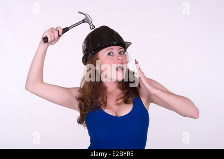 Giovane donna tenendo un martello e indossare un elmetto Foto Stock