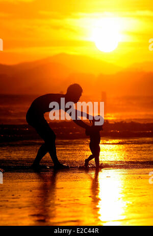 Sanya, cinese della provincia di Hainan. Il 18 giugno, 2014. Un bambino e il suo genitore giocare sulla spiaggia al tramonto di Sanya, Cina del sud della provincia di Hainan, 18 giugno 2014. Credito: Chen Wenwu/Xinhua/Alamy Live News Foto Stock