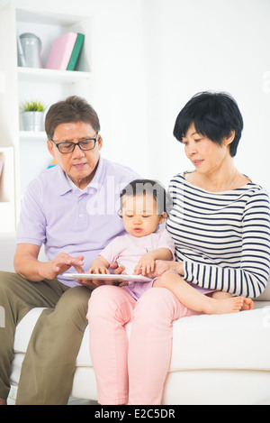 Asian grand genitori insegnare grand figlio internet con una compressa Foto Stock