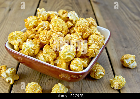 Caramello popcorn in un vaso di argilla su tavole di legno sfondo Foto Stock