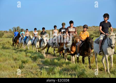 Francia, Herault, Serignan, Domaine des Orpellieres, passeggiata equestre nel mezzo di un salt marshes area, cavalier in unico file su un sentiero sabbioso Foto Stock