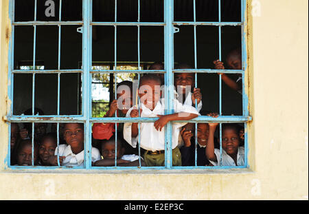 Tanzania, regione di Mwanza, Mwanza, bambini che cercano e sorridente attraverso una finestra della griglia della scuola Foto Stock