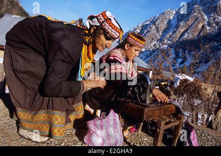 Il Pakistan Khyber Pakhtunkhwa Kalash valli valle Bumburet Krakal village (2150m) Kalash donne usando un vecchio manuale della macchina per cucire seduti sul tetto piatto di Kalash case per rinnovare il ricamo su i loro abiti lunghi Foto Stock