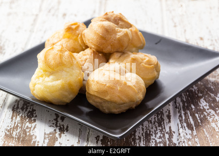 Eclair su nero piastra ceramica su uno sfondo di legno Foto Stock