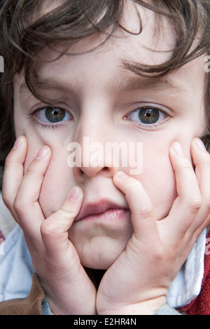 Ragazzo in appoggio mento nelle mani, espressione annoiata sul viso Foto Stock