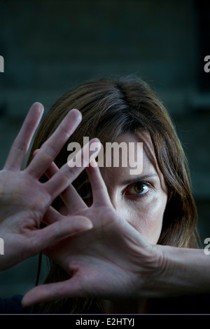 La donna alzando le mani per scongiurare un attacco Foto Stock