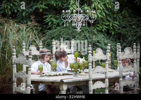 I bambini seduti a ornato tavolo da pranzo all'aperto Foto Stock