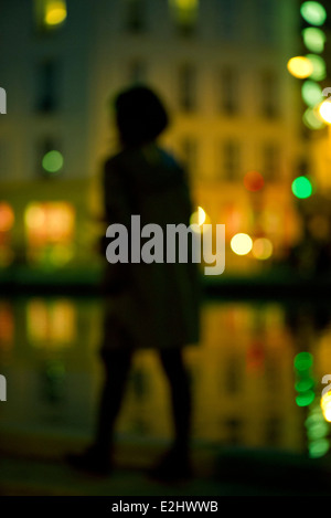 La donna a piedi di notte lungo urban riverside Foto Stock