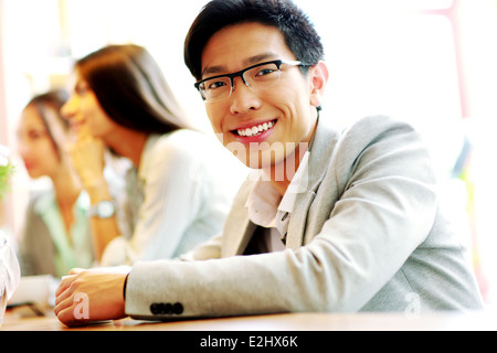 Ritratto di imprenditore sorridente seduto di fronte ai colleghi Foto Stock