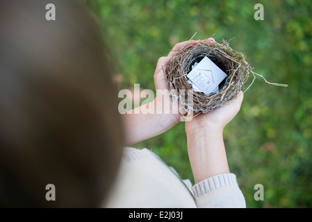 Bambino con le mani in mano azienda bird nest contenente il disegno della casa Foto Stock
