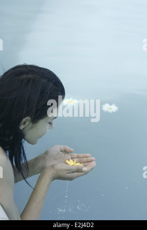 Giovane donna azienda fiore in mani a tazza Foto Stock