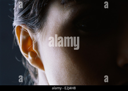Close-up di donna di orecchio, faccia la metà in ombra Foto Stock