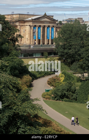 L uomo e la donna a piedi lungo un Princes Street Park giardini di fronte alla Scottish National Gallery, Edimburgo Foto Stock