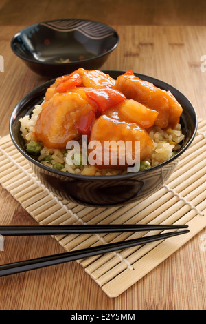 Dolce e aspro di pollo stile Cantonese con uovo fritto il riso in un recipiente di vernice con bacchette Foto Stock