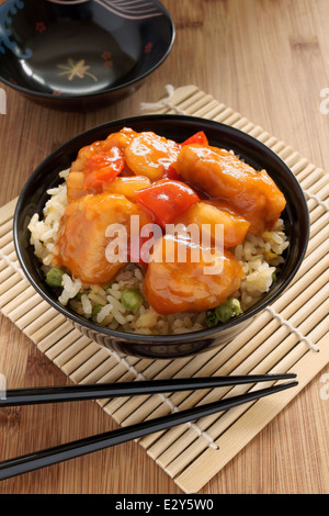 Dolce e aspro di pollo stile Cantonese con uovo fritto il riso in un recipiente di vernice con bacchette Foto Stock