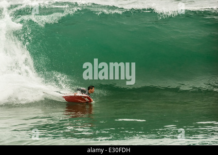 Bodyboarder carving un forte fondo girare su un enorme onda vetroso a cuneo in Newport Beach, California, Stati Uniti d'America. Foto Stock