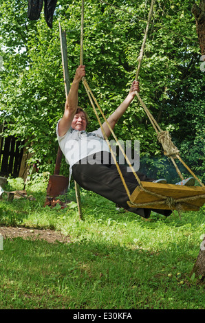 Rural Lifestyle estate 2013. La donna scuote su uno swing in un giardino rurale. Foto Stock