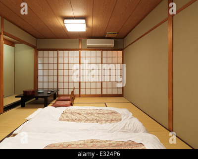 Tradizionale sala Giapponese in un ryokan con futon sul pavimento e un tavolo da tè. Kyoto, Giappone. Foto Stock