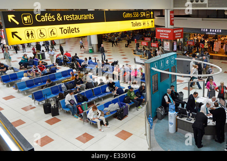 Area con posti a sedere sotto cafè, ristoranti e servizi igienici segni a Gatwick Airport North Terminal lounge di partenza e shopping concourse Foto Stock