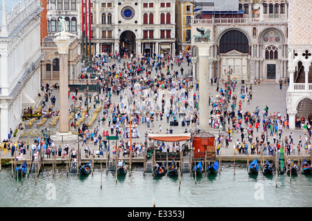 Vista verso il basso dalla nave da crociera con partenza da Venezia lungo il canale della Giudecca passando davanti al Palazzo Ducale occupato da turisti e gondole lungo il Molo Foto Stock