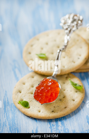 Caviale rosso in cucchiaio sul cracker, closeup, il fuoco selettivo Foto Stock