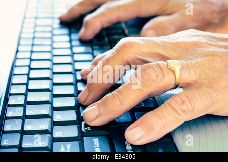 Vecchio mani femminili digitando sulla tastiera del computer.Il fuoco selettivo sul secondo dito Foto Stock