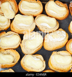 Vista dall'alto di molti pezzi di arrosto di pane con fuso formaggio di capra sul vassoio a caldo Foto Stock