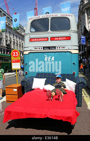 Londra, Regno Unito. Il 22 giugno 2014. James da Australia rilassante su un letto accanto all'AEC BEA Coach MLL740 autobus in servizio 1953-1973 all'anno di Bus cavalcata in Regent Street, Londra celebra il ruolo gli autobus hanno svolto nel movimento di persone intorno a Londra. Gli autobus erano sul display dal 1829 ad oggi. Foto Stock