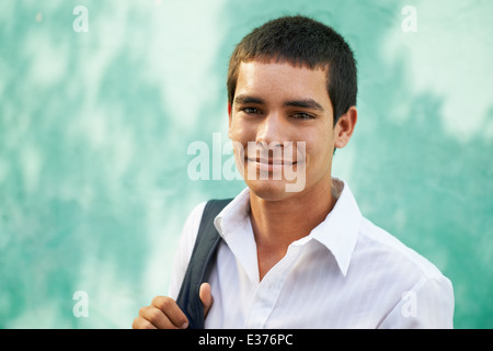 Ritratto di giovane maschio ispanico studente sacco di contenimento e sorridente in telecamera sorridente. Spazio di copia Foto Stock