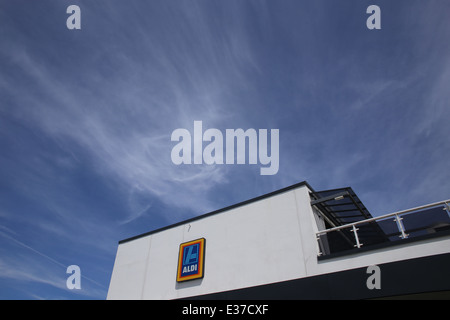 Un supermercato Aldi logo montato sulla parete del negozio, con un cielo blu e nuvole in background. Foto Stock