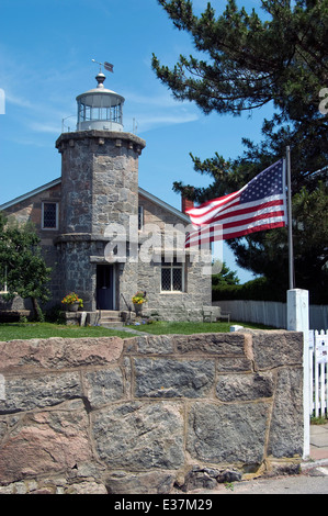 Bandiera americana onde nella parte anteriore del Stonington faro del porto. Il faro è ora una biblioteca e un museo per la sua Connecticut residenti. Foto Stock