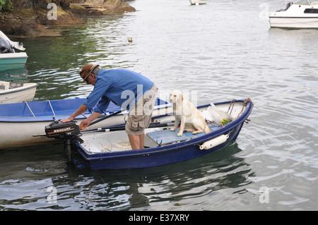 Uomo con cane in barca in Bantham nel sud prosciutti, Devon, Regno Unito Foto Stock