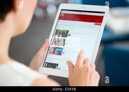 Donna che mantiene un marchio nuovo Apple iPad aria e cercando su YouTube music playlist su una schermata Foto Stock