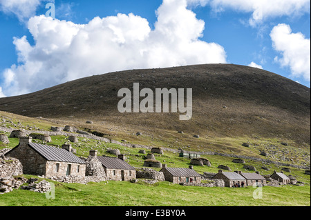 I turisti ad esplorare il blackhouses abbandonati nella strada principale nel Villaggio Baia, St. Kilda Foto Stock