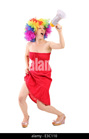 A piena lunghezza Ritratto di una donna con parrucca urlando su un megafono Foto Stock