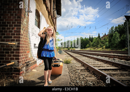 Ragazza di attesa per il treno sulla stazione ferroviaria Foto Stock