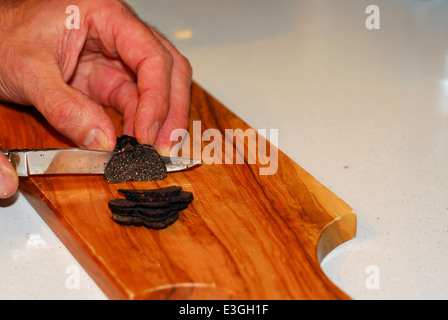 Una persona che il taglio di un tartufo nero Foto Stock