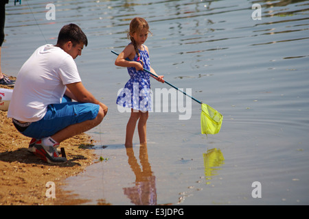 L'uomo con la giovane ragazza in piedi in acqua con net pescato granchi presso il porto di Poole in giugno Foto Stock