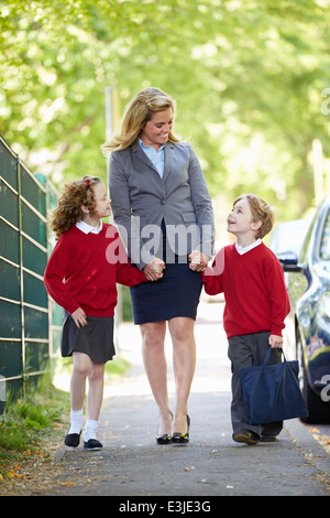 Madre andare a scuola a piedi con i bambini sulla strada per il lavoro Foto Stock