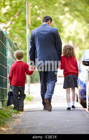 Padre andare a scuola a piedi con i bambini sulla strada per il lavoro Foto Stock