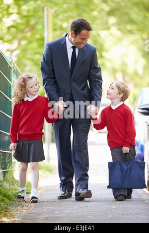 Padre andare a scuola a piedi con i bambini sulla strada per il lavoro Foto Stock