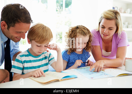 I genitori aiutano i bambini con i compiti in cucina Foto Stock